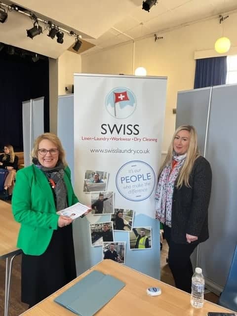 Two women standing in front of a table with a swiss sign.
