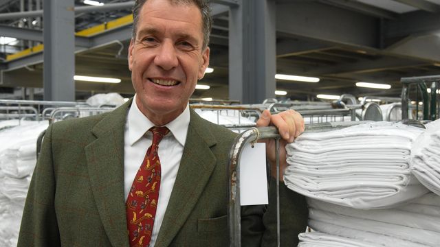 A man in a suit and tie standing next to a rack of clothes.