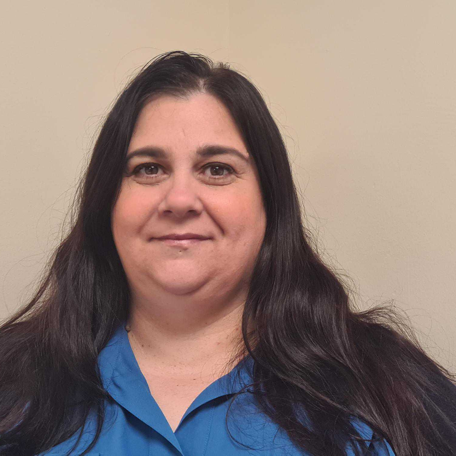A woman in a blue shirt is smiling.